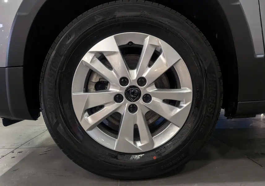 Gros plan sur la roue avant droite avec jante alliage argentée du Peugeot Rifter gris acier 2025.