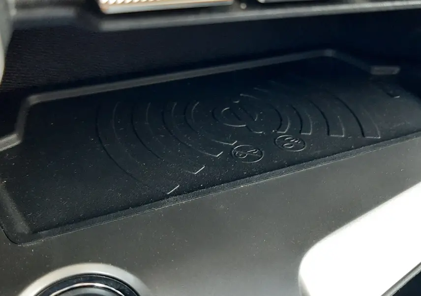 Détail du plateau de recharge sans fil et bouton start/stop dans l'habitacle de la Peugeot 408 Hybrid gris selenium, vue rapprochée.