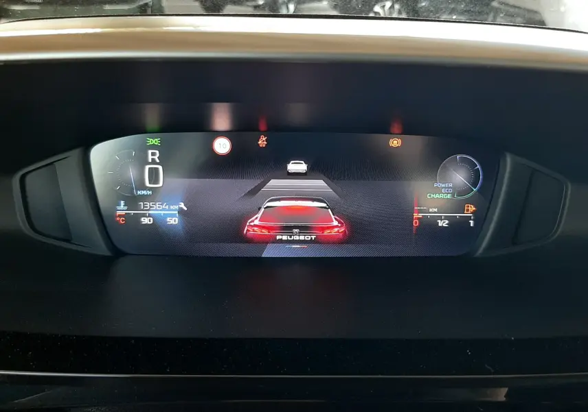 Affichage numérique du tableau de bord de la Peugeot 408 Hybrid 2024, avec indicateurs de vitesse, énergie et assistance.