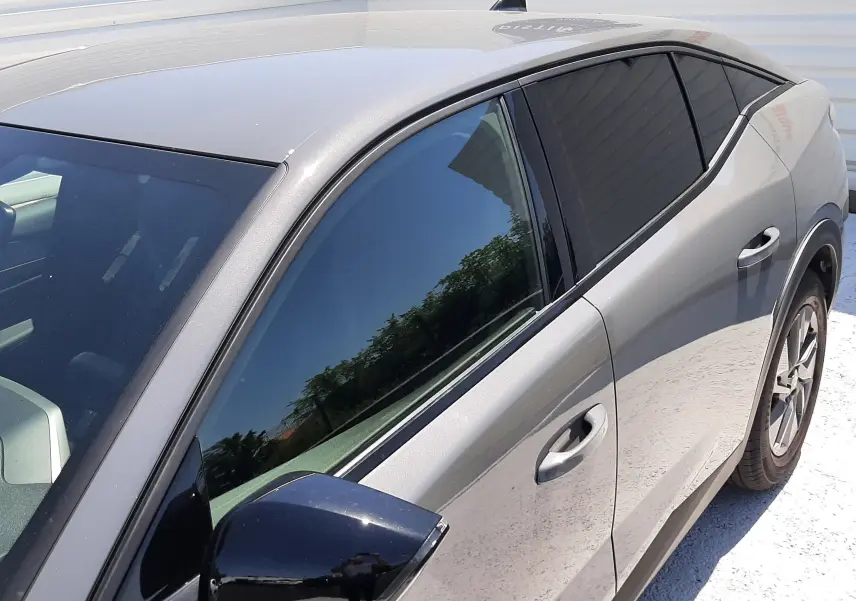 Vue de côté droit avant d'une Peugeot 408 gris selenium avec rétroviseur noir et vitres teintées.