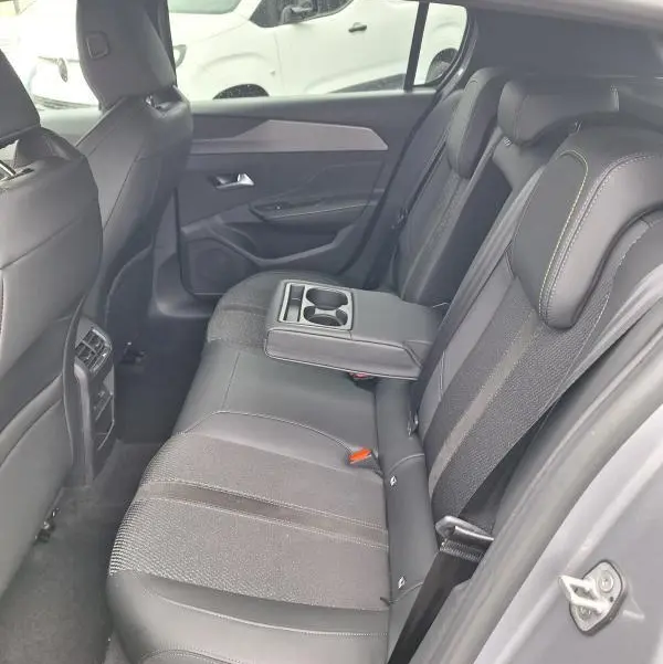 Vue intérieure côté gauche des sièges arrière gris du Peugeot 308 Hybrid 145 e-DCS6 GT avec accoudoir central et porte-gobelets.