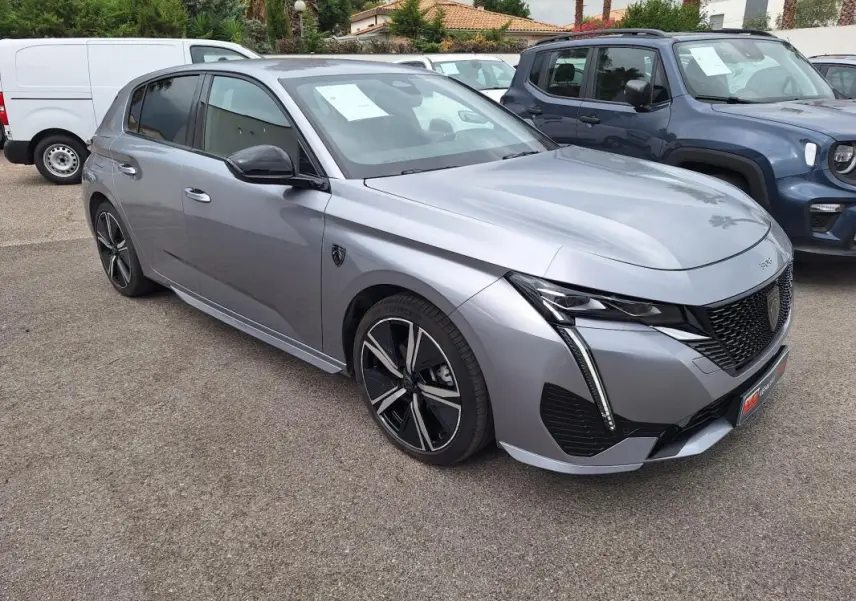 Peugeot 308 Hybrid gris en 3/4 avant droit, avec jantes alliage 18 pouces et signature lumineuse verticale LED.