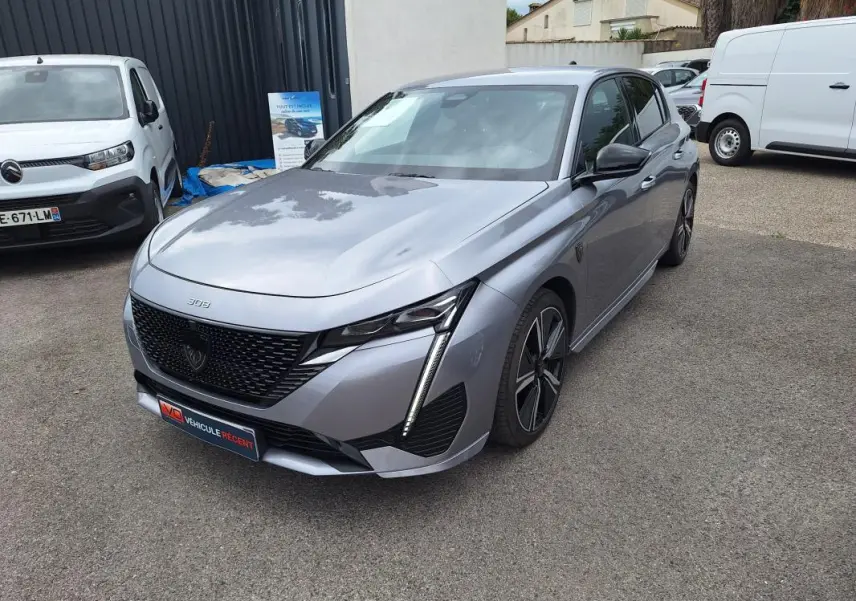 PEUGEOT 308 Hybrid gris en 3/4 avant droit, avec calandre noire et jantes alliage 18 pouces visibles.