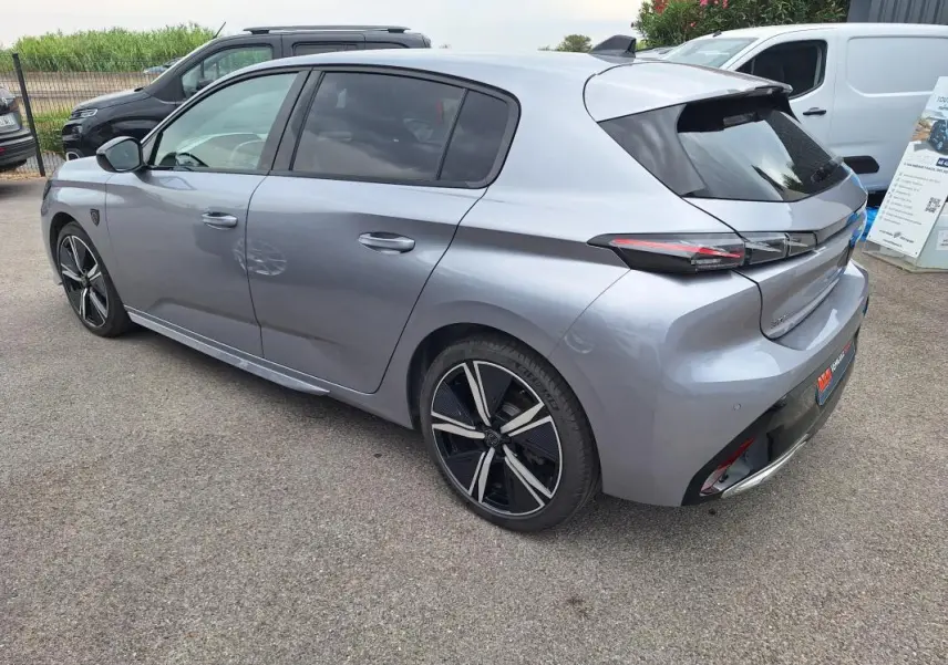 Vue 3/4 arrière droite d'une Peugeot 308 Hybrid 145 e-DCS6 GT gris avec jantes alliage 18 pouces et vitres teintées.