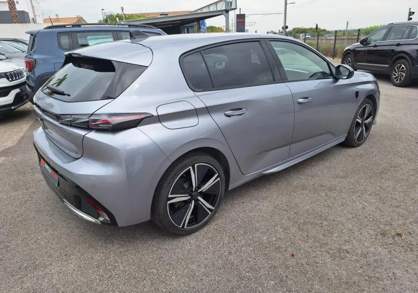 Peugeot 308 Hybrid gris vue 3/4 arrière droit, jantes alliage 18 pouces et vitres teintées visibles.