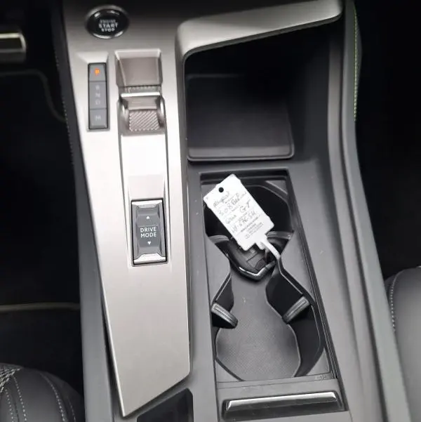 Vue plongeante sur la console centrale grise de la Peugeot 308 Hybrid 145 e-DCS6 GT avec levier de vitesses et porte-gobelets.