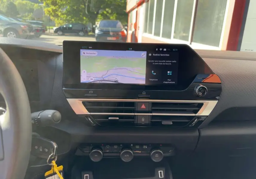 Vue intérieure du tableau de bord de la Citroën C4 hybride 2025, avec écran tactile de navigation et commandes de climatisation.