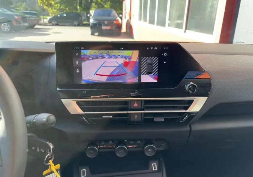 Vue intérieure du tableau de bord de la Citroën C4 hybride 2025 avec écran de caméra de recul et commandes climatisation.