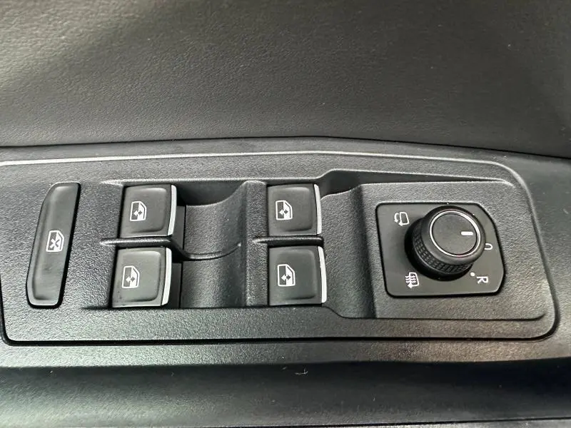 Commandes des vitres électriques et réglage des rétroviseurs sur la portière côté conducteur d'un Volkswagen T-Roc gris 2025.