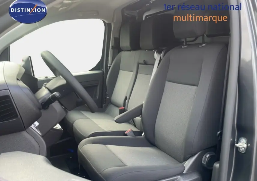 Vue intérieure côté conducteur du Citroën Jumpy gris titane, montrant les sièges tissu gris et le volant multifonction.