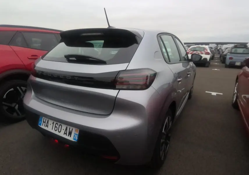Vue 3/4 arrière droite d'une Peugeot 208 gris clair 2024, avec feux arrière fumés et toit noir contrastant.