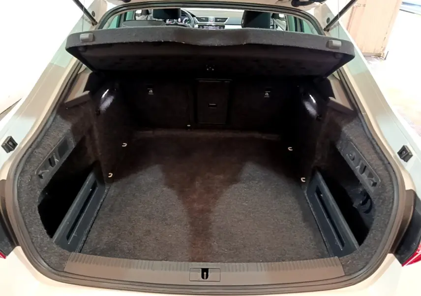 Vue intérieure du coffre ouvert d'une Skoda Superb blanche 2021, montrant un espace de rangement propre et spacieux.