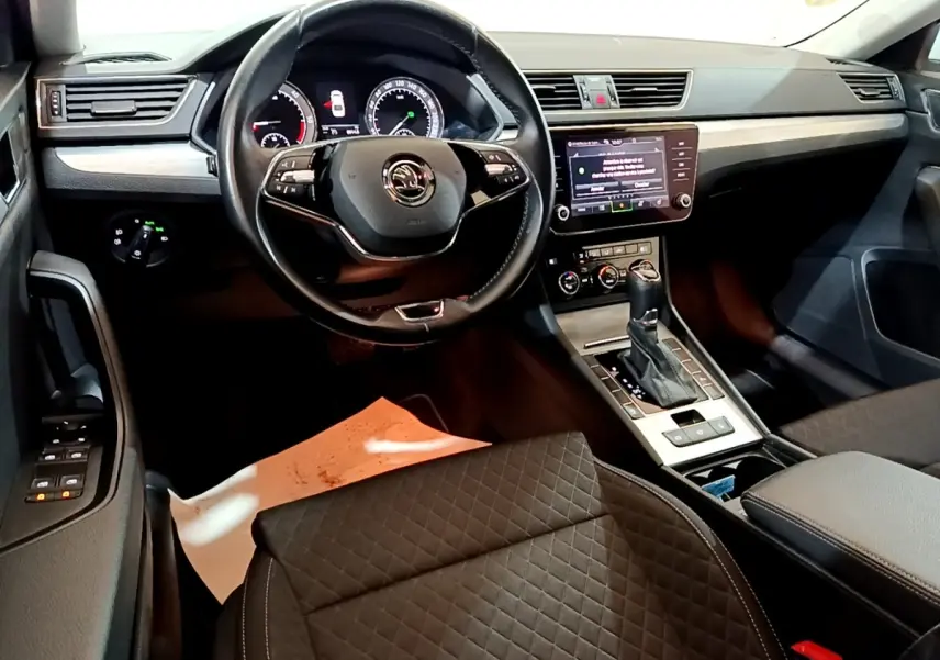 Vue intérieure côté conducteur de la Skoda Superb 2021, tableau de bord noir avec écran tactile et volant cuir multifonctions.