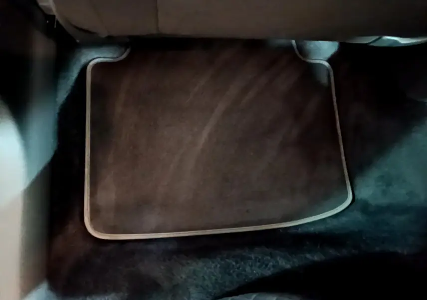 Tapis de sol noir avec bordure beige dans l'habitacle arrière d'une Skoda Superb blanche, vue du plancher arrière.