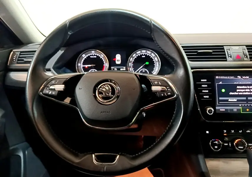 Vue intérieure centrée sur le volant cuir noir de la Skoda Superb 2.0 TDI 2021 avec tableau de bord digital et écran tactile.