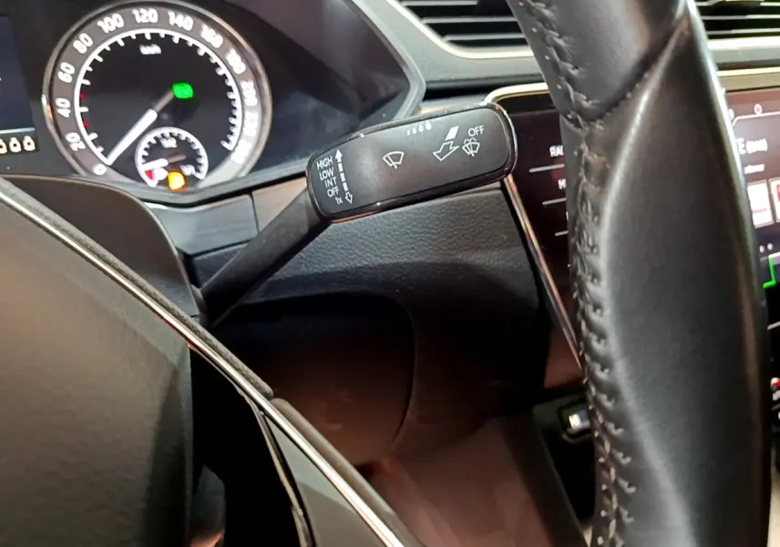 Gros plan sur le commodo d’essuie-glace et le volant cuir de la Skoda Superb 2.0 TDI 2021, tableau de bord partiellement visible.