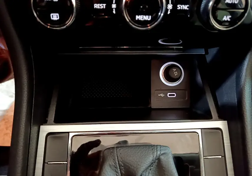 Gros plan sur la console centrale de la Skoda Superb blanche, montrant la prise 12V, port USB et commandes climatisation.