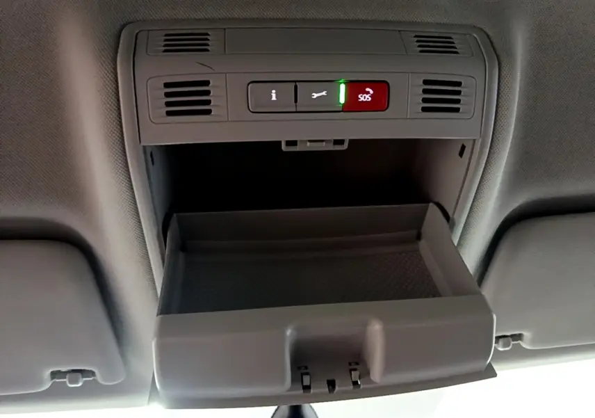 Vue intérieure en plongée du compartiment lunettes ouvert et des boutons SOS et assistance dans le plafond d'une Skoda Superb blanche.