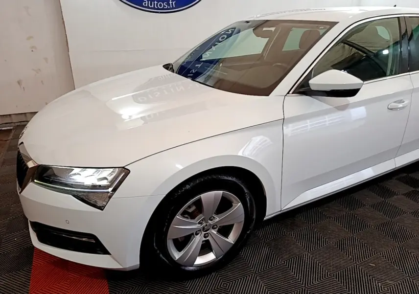 Vue 3/4 avant droit d'une Skoda Superb blanche avec phares LED et jantes alliage argentées.