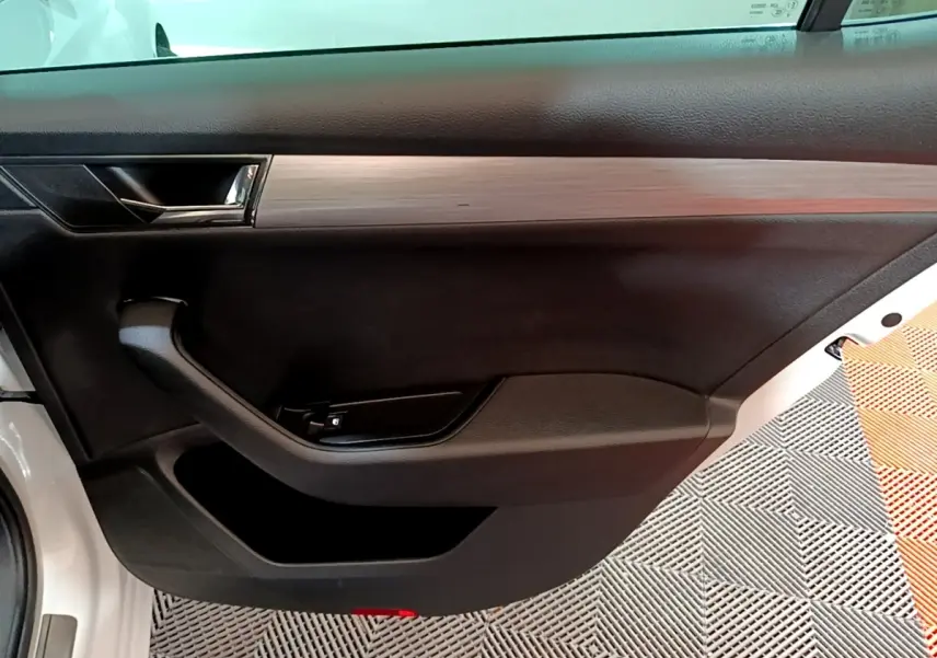 Vue rapprochée de la porte avant gauche blanche d'une Skoda Superb 2021 avec garniture noire et insert imitation bois.