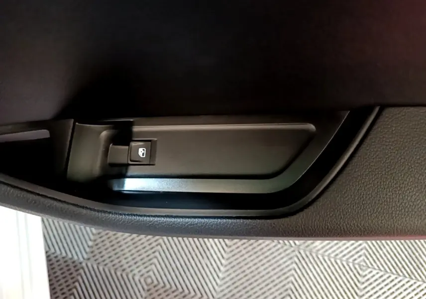 Gros plan sur la poignée intérieure noire de porte arrière droite de la Skoda Superb blanche, avec bouton de verrouillage.