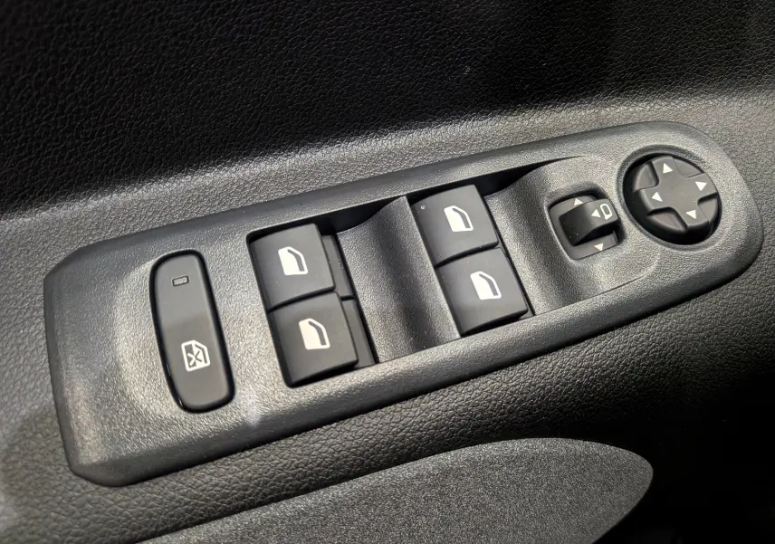 Gros plan sur les commandes électriques des vitres et rétroviseurs côté conducteur du Peugeot Rifter noir 2025.