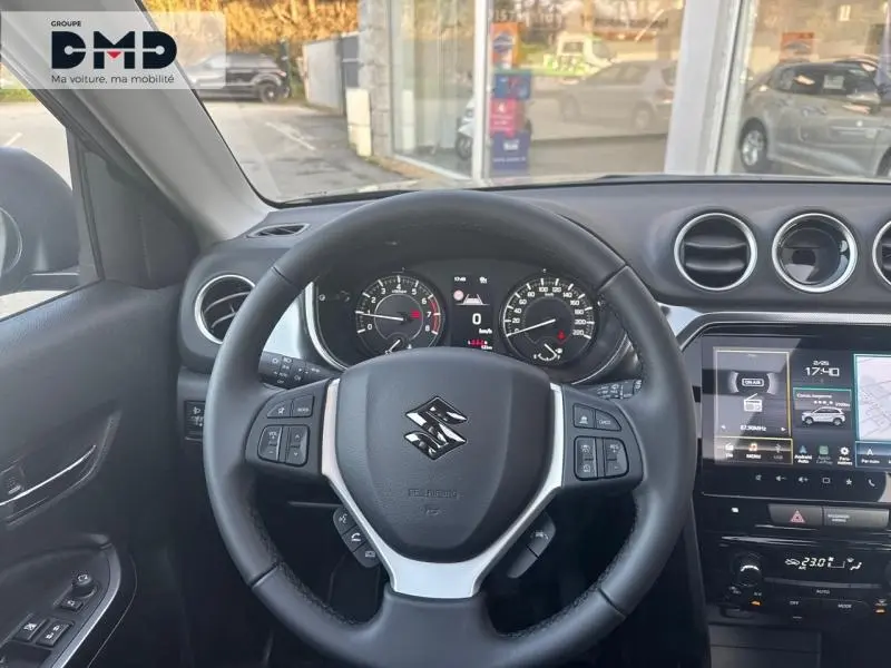 Vue intérieure centrée sur le volant cuir multifonction du Suzuki Vitara 1.4 Boosterjet Hybrid, avec tableau de bord et écran tactile.