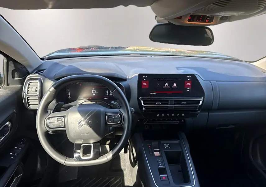 Vue intérieure avant du tableau de bord noir du Citroën C5 Aircross 2025 avec volant multifonction et écran tactile central.