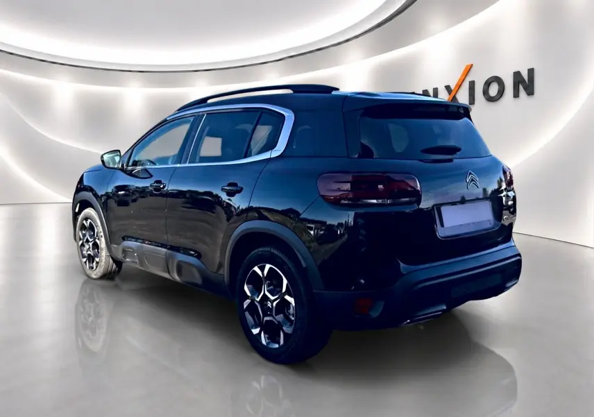Citroën C5 Aircross noir vue 3/4 arrière droit, jantes alu et barres de toit visibles dans un studio lumineux.