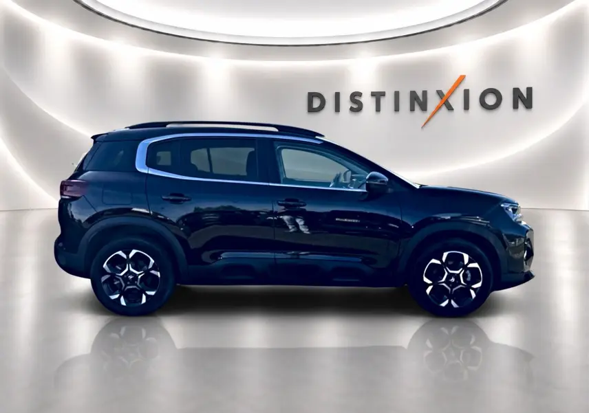 Vue de profil côté gauche d'un Citroën C5 Aircross noir 2025 dans un showroom lumineux avec jantes alu distinctives.