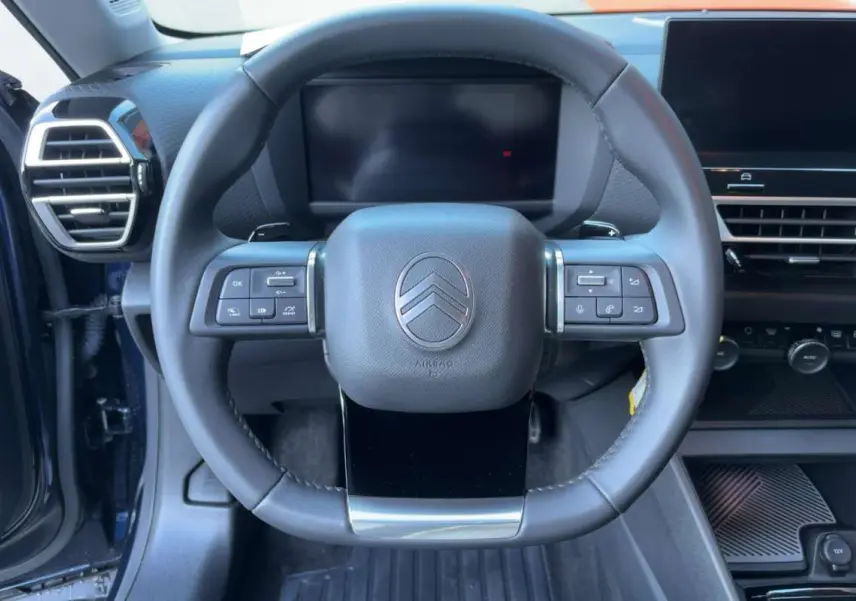 Vue frontale du volant cuir multifonctions de la Citroën C4 hybride bleu eclipse, avec tableau de bord numérique et écran tactile.
