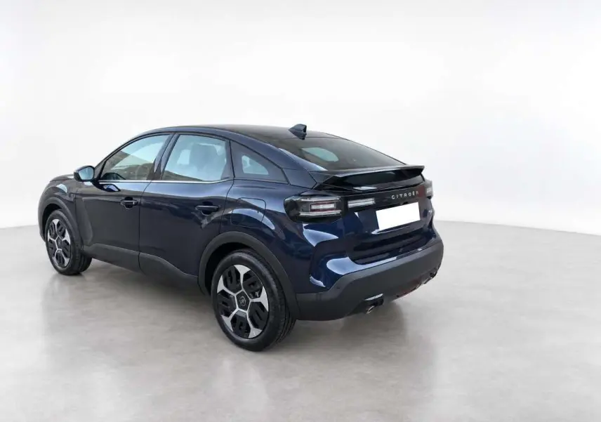 Vue 3/4 arrière droite d'une Citroën C4 hybride 2025 bleu eclipse avec toit noir et feux arrière LED distinctifs.