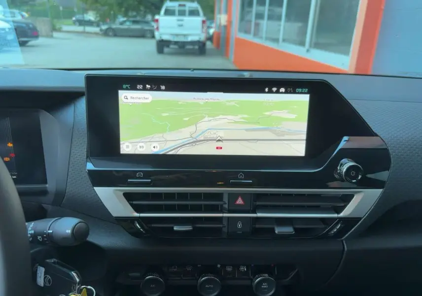 Vue intérieure du tableau de bord de la Citroën C4 hybride 2025 avec écran tactile de navigation et commandes de climatisation.