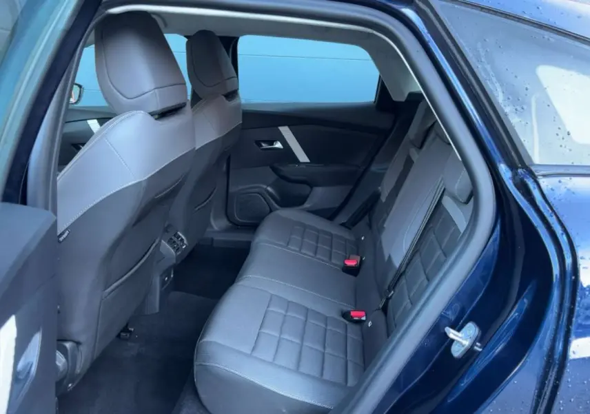 Vue intérieure arrière côté gauche de la Citroën C4 hybride 2025 bleu eclipse, montrant la banquette et les dossiers avant.