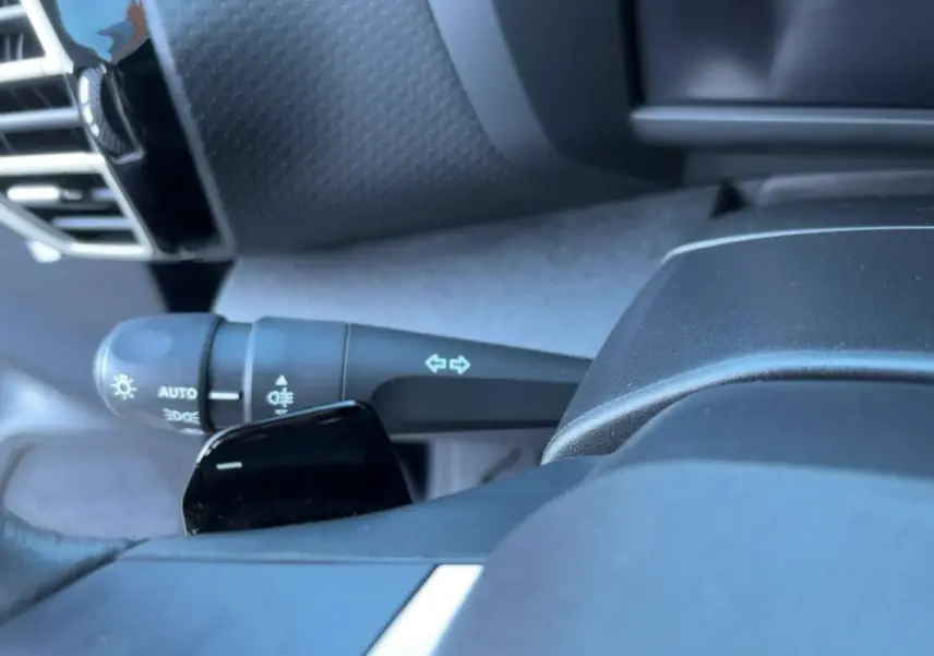Gros plan sur la commande des feux et clignotants côté gauche du volant cuir du Citroën C4 hybride 2025.
