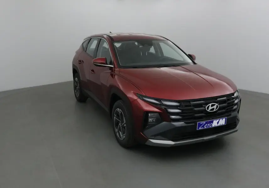 Vue 3/4 avant gauche du Hyundai Tucson 2025 rouge Ultimate avec calandre noire et jantes alliage 17 pouces.