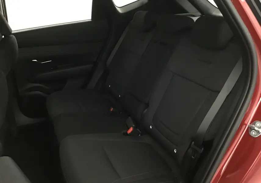 Vue intérieure arrière droite du Hyundai Tucson 2025 rouge Ultimate, montrant les sièges arrière noirs en tissu.