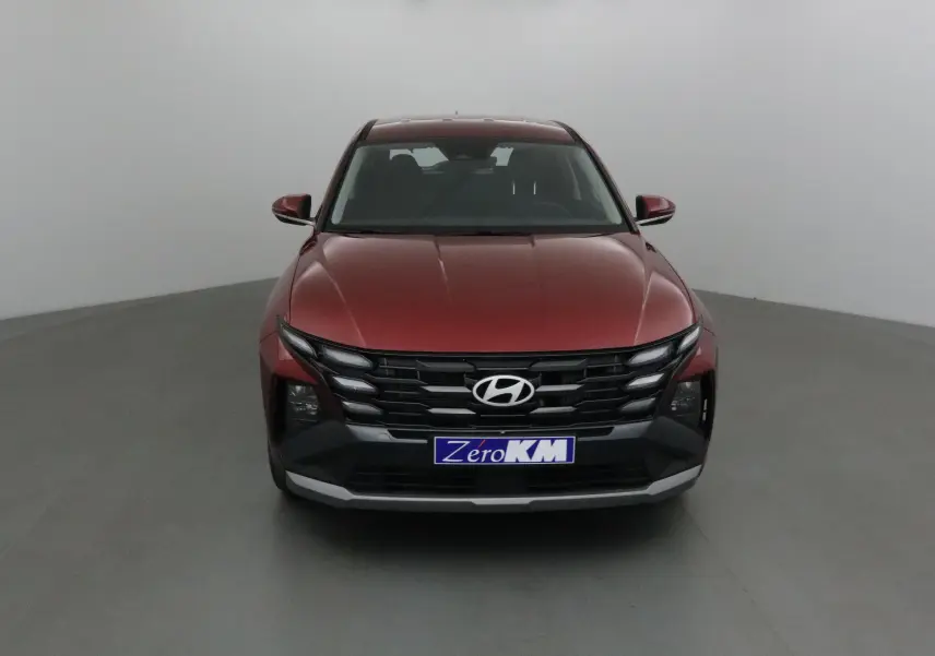 Vue frontale d'un Hyundai Tucson 2025 rouge Ultimate avec calandre noire et plaque Zero KM visible.