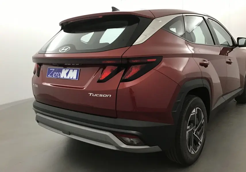 Vue 3/4 arrière droite du Hyundai Tucson rouge Ultimate 2025 avec feux arrière LED et jantes alliage noires.