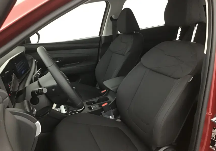 Vue intérieure côté conducteur du Hyundai Tucson 2025 rouge Ultimate, montrant sièges noirs et tableau de bord moderne.