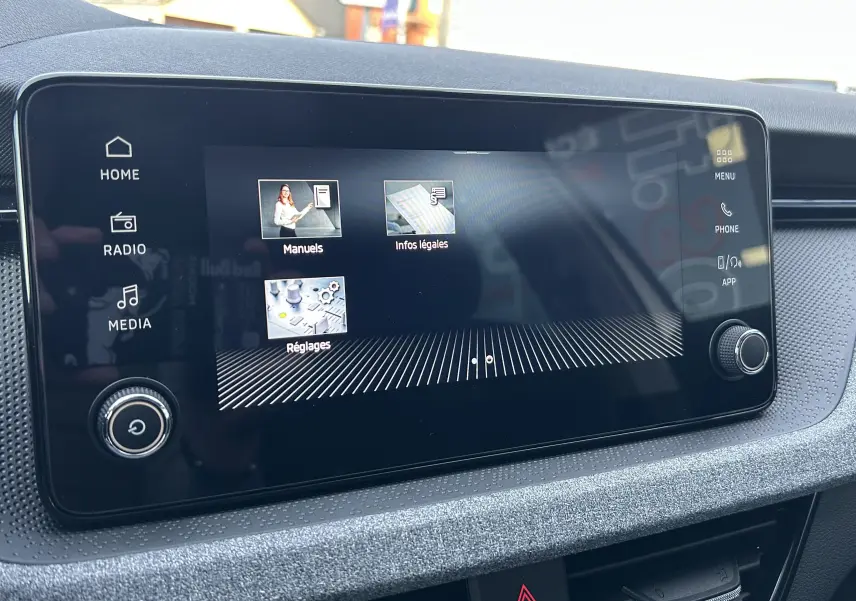 Écran tactile central du Skoda Kamiq 2025 gris argent, affichant les menus manuels, infos légales et réglages.