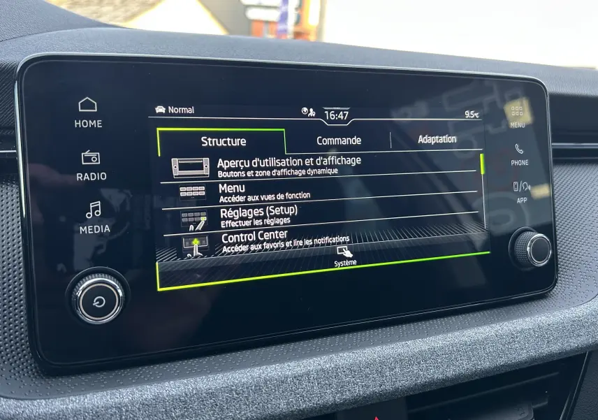 Écran tactile central du Skoda Kamiq 2025 affichant le menu de réglages, avec tableau de bord gris et commandes autour.