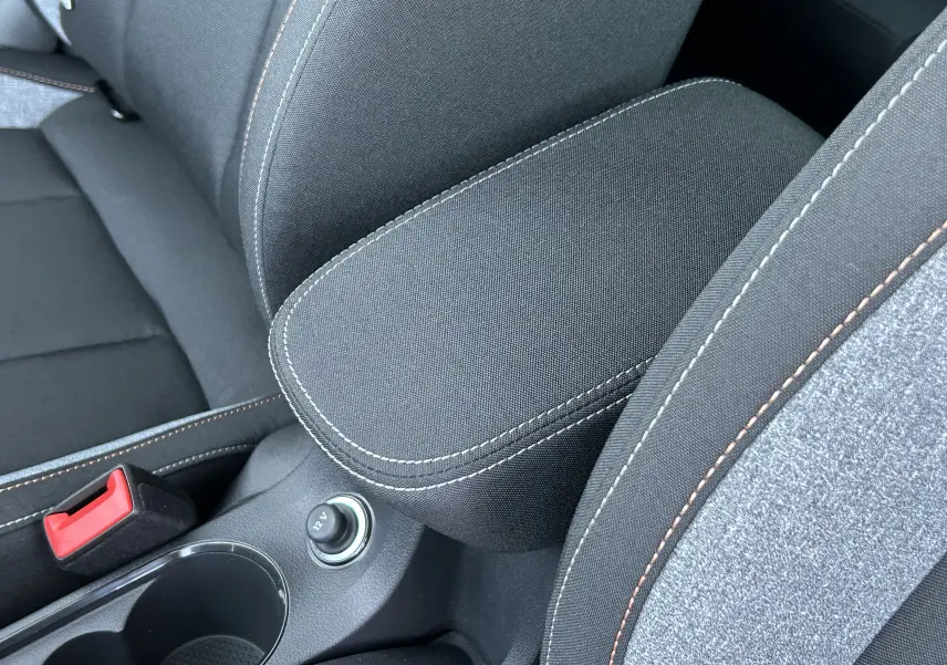 Gros plan sur l'accoudoir central et les sièges en tissu gris noir avec surpiqûres contrastantes du Skoda Kamiq 2025.