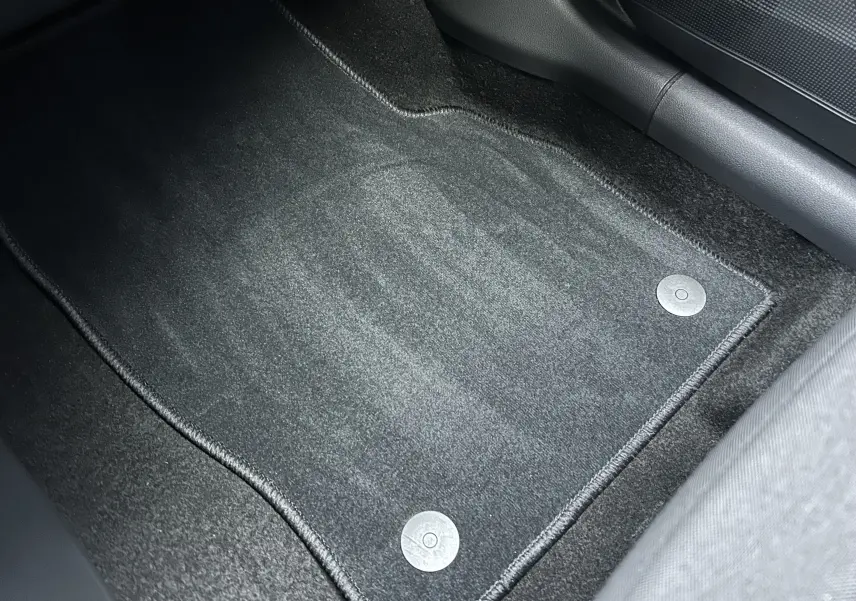 Vue rapprochée du tapis de sol gris foncé à fixation circulaire dans l'habitacle d'un Skoda Kamiq 2025 gris argent métallisé.