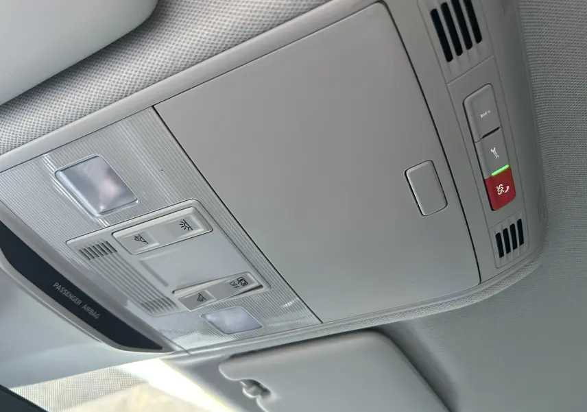 Vue intérieure du plafonnier gris clair du Skoda Kamiq 2025 avec commandes d'éclairage et bouton d'urgence rouge.