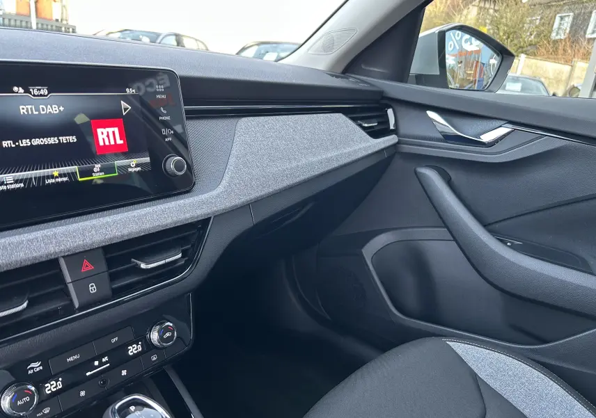 Vue intérieure côté passager du Skoda Kamiq gris argent, mettant en valeur la planche de bord moderne et l’écran tactile.
