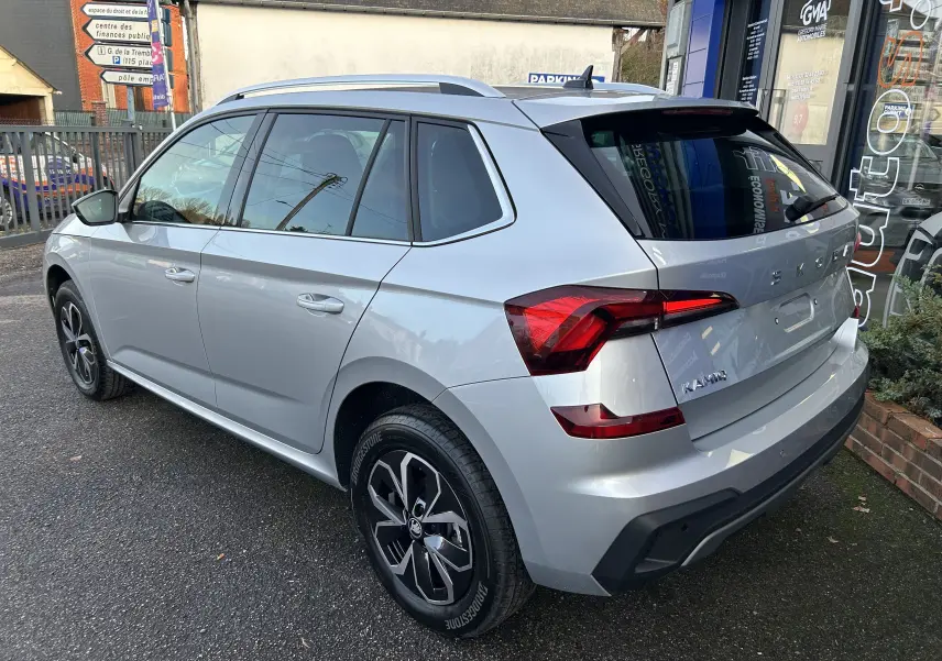 Vue 3/4 arrière droite d'un Skoda Kamiq gris argent métallisé avec feux arrière LED et jantes alliage noires.