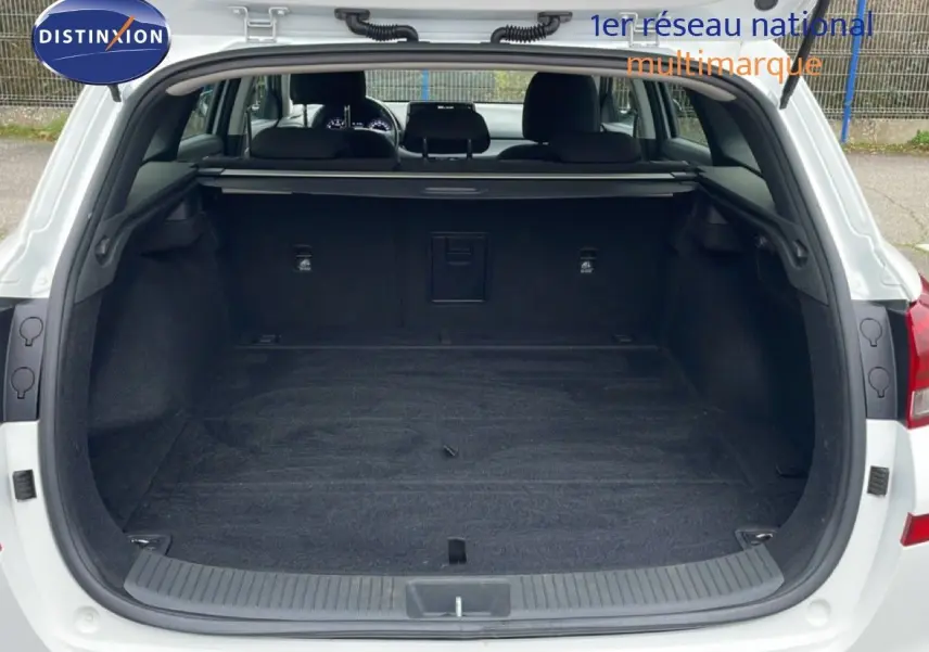 Coffre ouvert d'une Hyundai i30 SW blanc atlas, vue arrière montrant l'espace de chargement vide et la plage arrière.
