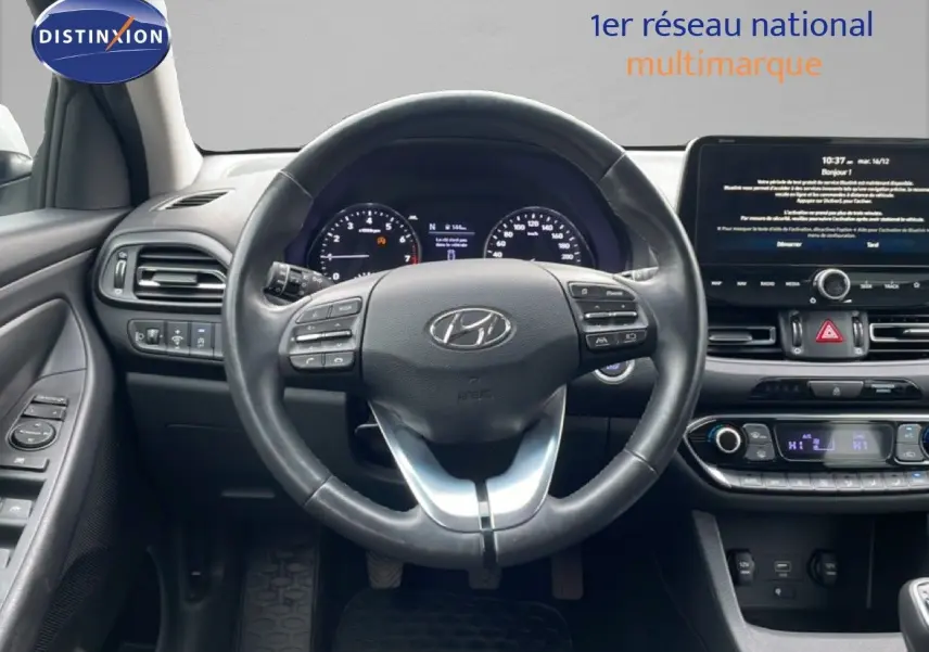 Vue intérieure centrée sur le volant cuir noir et le tableau de bord digital de la Hyundai i30 SW 2023.