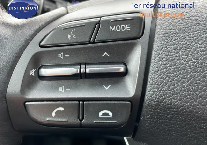 Gros plan sur les commandes multifonctions au volant du Hyundai i30 SW 2023, finition Family Smart, intérieur noir.
